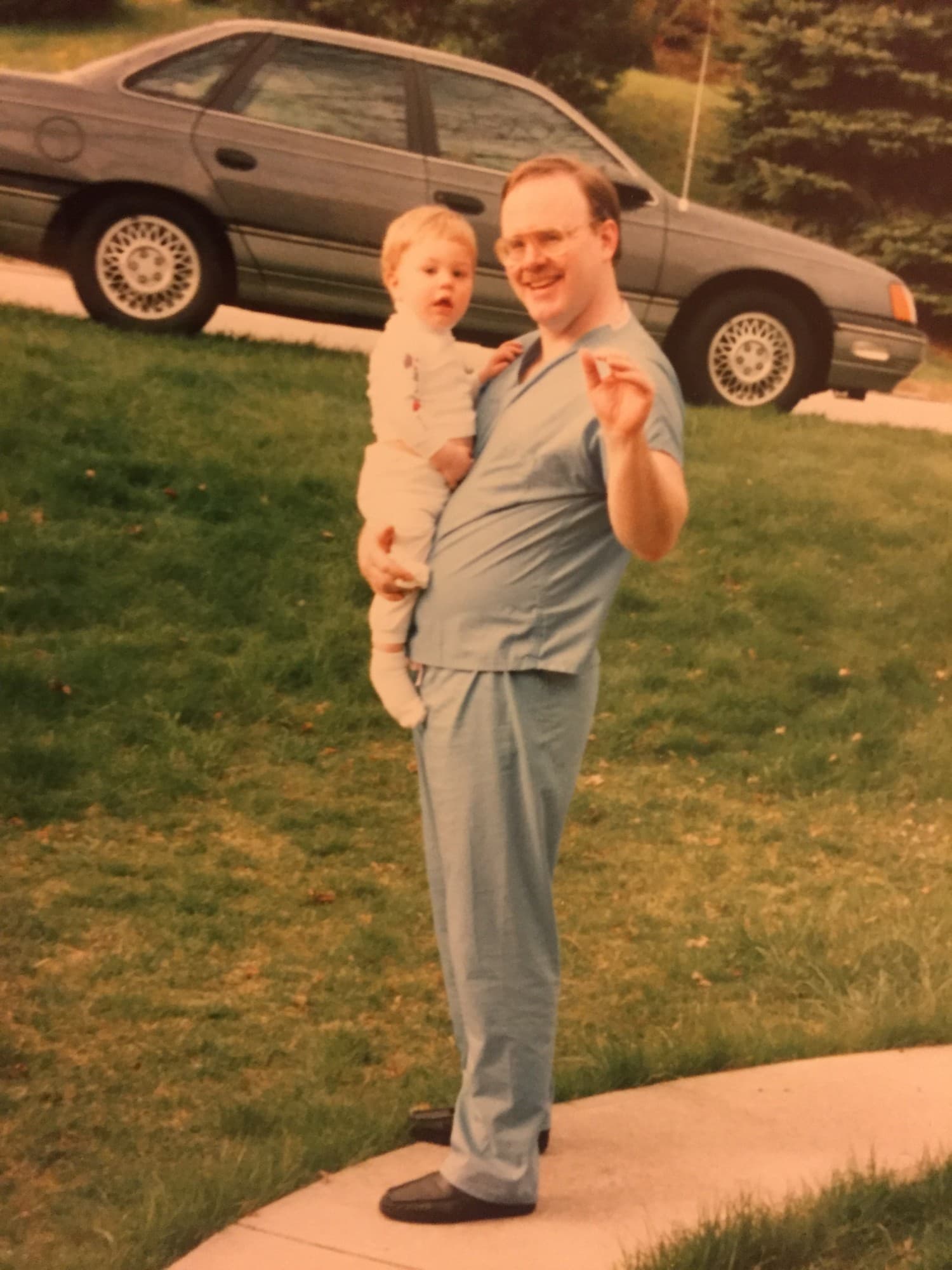 Dr. Tagge as a toddler, held by his father in surgical scrubs